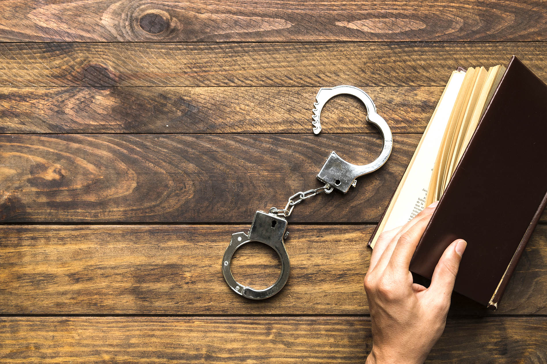 Handcuffs resting on a wooden desk beside a legal book